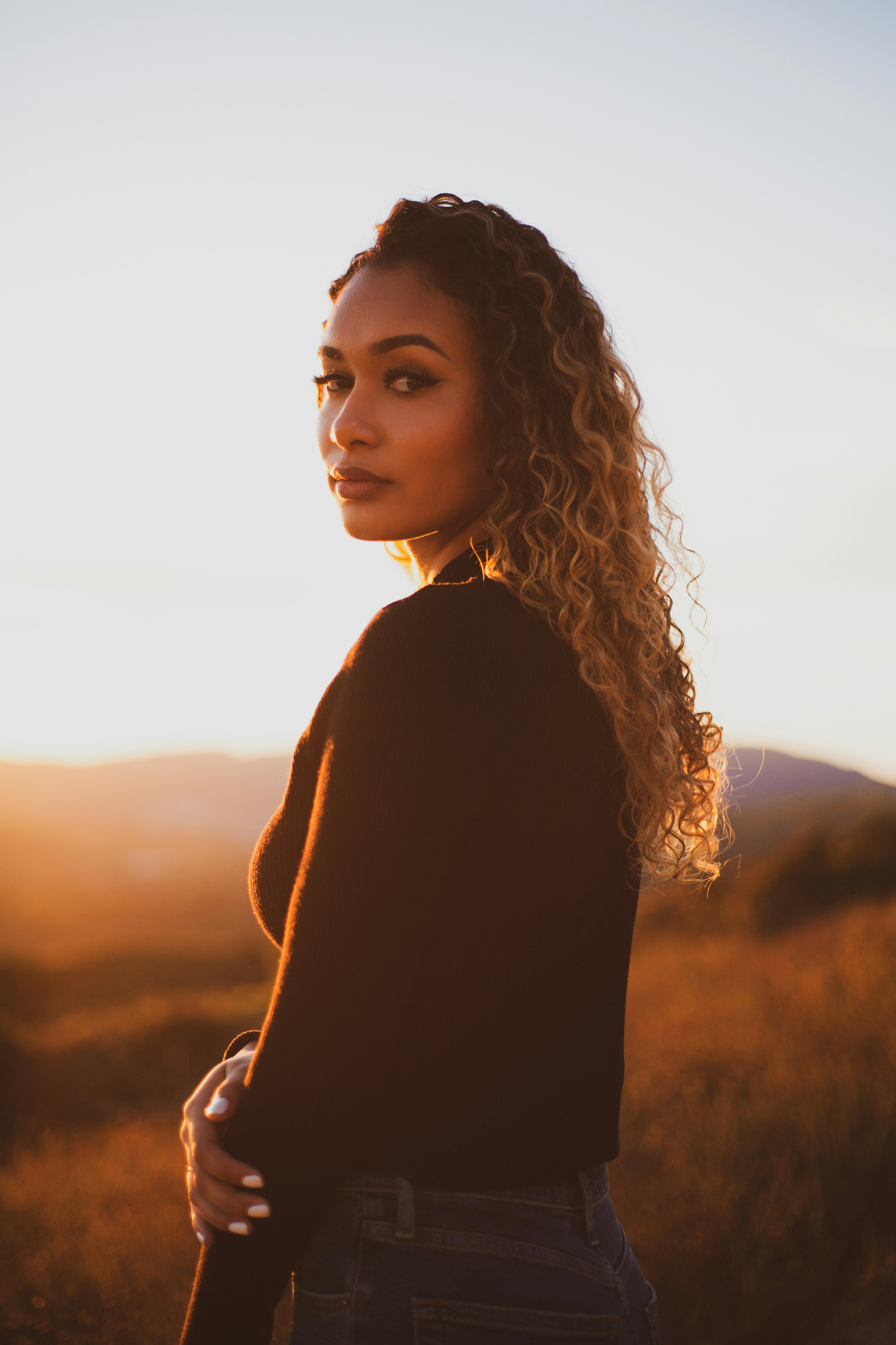Woman silhouetted against a pink sunset window